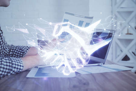 Handshake hologram drawing with businessman working on computer on background. Double exposure.の写真素材