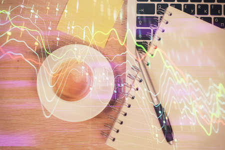 Double exposure of financial chart drawing over table background with computer. Concept of research and analysis. Top view.の写真素材