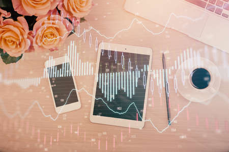 Double exposure of forex graph hologram over desktop with phone. Top view. Mobile trade platform...