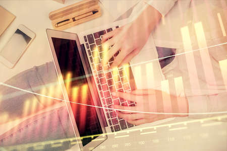 Double exposure of woman hands working on computer and forex graph hologram drawing. Top View....