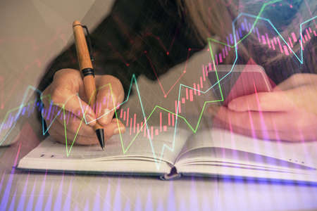 Double exposure of businesswoman hands typing on computer and forex graph hologram drawing. Financial analysis concept.の写真素材