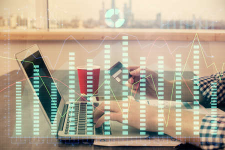Double exposure of man hands holding a credit card and Forex graph drawing. Stock trading and...