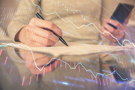 Double exposure of forex chart sketch hologram and woman holding and using a mobile device....