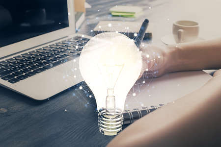 Drawing bulb over womans hands taking notes background. Concept of idea. Double exposure