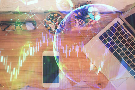 Double exposure of financial graph hologram over desktop with phone. Top view. Mobile trade platform...