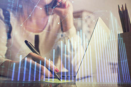 Double exposure of woman hands typing on computer and financial graph hologram drawing. Stock market analysis concept.の写真素材