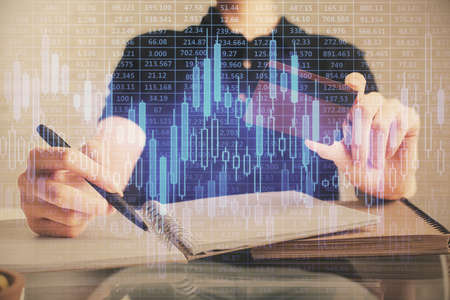 Double exposure of man hands holding a credit card and Forex graph drawing. Stock trading and...