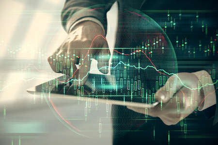 Double exposure of man's hands holding and using a digital device and forex graph drawing. Financial...