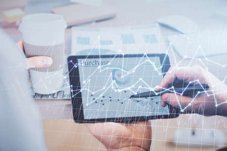 Double exposure of man's hands holding and using a phone and financial chart drawing. Market...