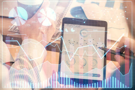 Double exposure of man's hands holding and using a phone and financial chart drawing. Market...