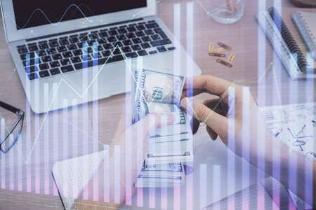 Multi exposure of financial graph drawing hologram and USA dollars bills and man hands. Analysis...