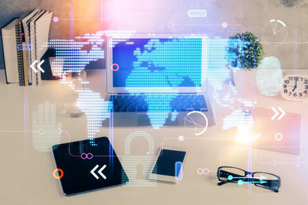 Double exposure of desktop with computer and world map hologram. International data network concept.の写真素材