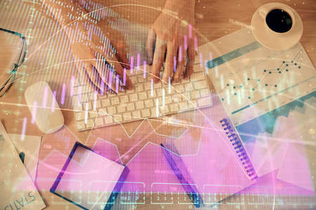 Multi exposure of man's hands typing over computer keyboard and forex graph hologram drawing. Top...