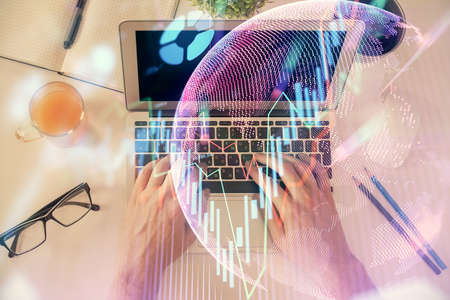 Double exposure of man's hands typing over laptop keyboard and forex chart hologram drawing. Top view. Financial markets concept.の写真素材