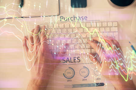 Double exposure of man's hands typing over laptop keyboard and forex chart hologram drawing. Top...