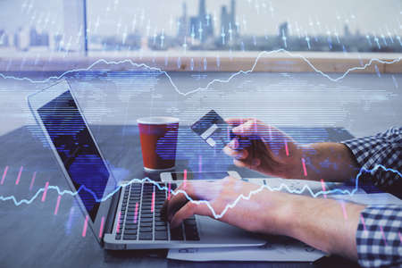 Double exposure of man hands holding a credit card and Forex graph drawing. Stock trading and...