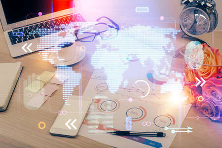 Double exposure of desktop with computer and world map hologram. International data network concept.