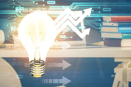 Computer on desktop in office with bulb icon hologram. Double exposure. Concept of idea.