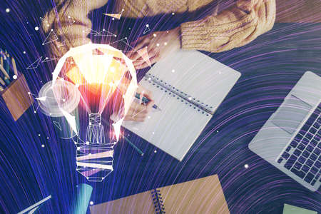 Drawing bulb over woman's hands taking notes background. Concept of idea. Double exposure