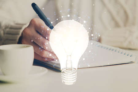 Drawing bulb over woman's hands taking notes background. Concept of idea. Double exposure