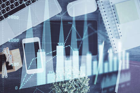 Double exposure of forex chart hologram over desktop with phone. Top view. Mobile trade platform...