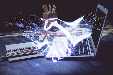 Desktop computer background in office and handshake hologram drawing. Double exposure. Pertnership...