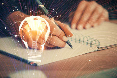 Drawing bulb over woman's hands taking notes background. Concept of idea. Double exposure