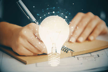 Drawing bulb over woman's hands taking notes background. Concept of idea. Double exposureの写真素材