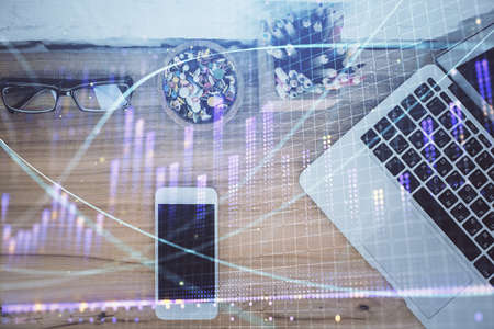 Double exposure of financial graph hologram over desktop with phone. Top view. Mobile trade platform concept.の写真素材