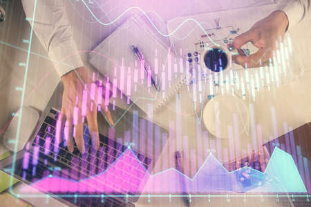 Multi exposure of man's hands typing over computer keyboard and forex graph hologram drawing. Top...