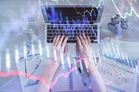 Double exposure of woman hands working on computer and forex graph hologram drawing. Top View....
