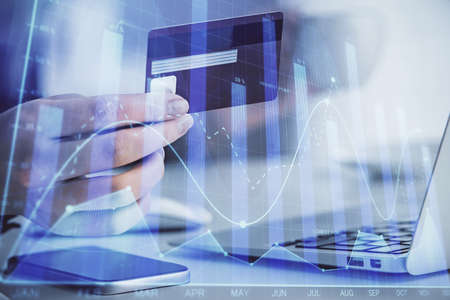 Multi exposure of woman on-line shopping holding a credit card and financial graph drawing. Stock...