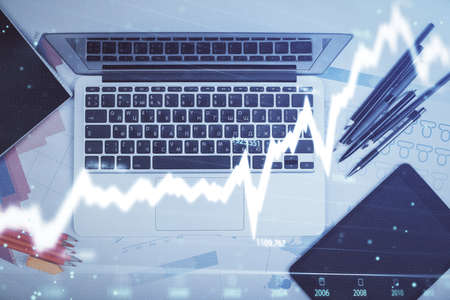Multi exposure of forex chart drawing over table background with computer. Concept of financial...
