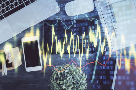 Double exposure of forex chart hologram over desktop with phone. Top view. Mobile trade platform...