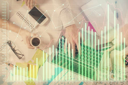 Multi exposure of man's hands typing over computer keyboard and forex graph hologram drawing. Top view. Financial markets concept.の写真素材