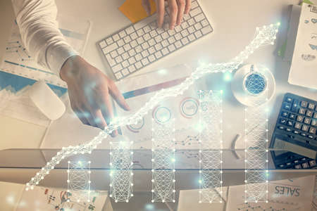 Multi exposure of man's hands typing over computer keyboard and forex graph hologram drawing. Top view. Financial markets concept.の写真素材