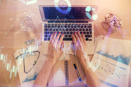 Double exposure of woman hands working on computer and forex graph hologram drawing. Top View. Financial analysis concept.の写真素材