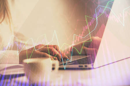 Double exposure of woman hands working on computer and forex graph hologram drawing. Financial...