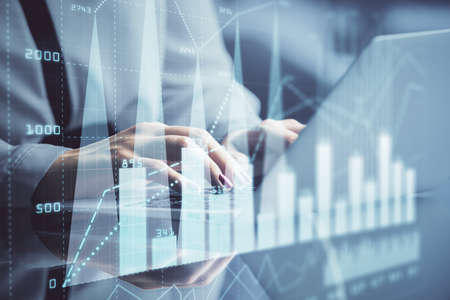 Double exposure of businesswoman hands typing on computer and financial graph hologram drawing. Stock market analysis concept.の写真素材