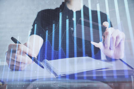 Double exposure of man hands holding a credit card and Forex graph drawing. Stock trading and digital fintech in Internet E-commerce concept.の写真素材