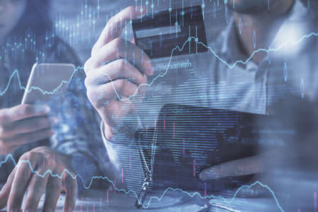 Double exposure of man and woman on-line shopping holding a credit card and forex graph hologram...