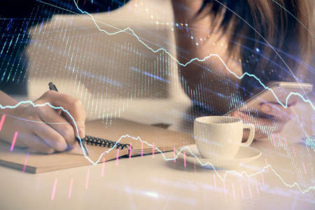 Double exposure of forex graph sketch hologram and woman holding and using a mobile device. Stock...