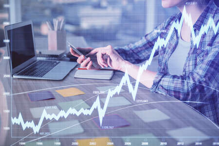 Double exposure of businesswoman hands typing on computer and forex graph hologram drawing....