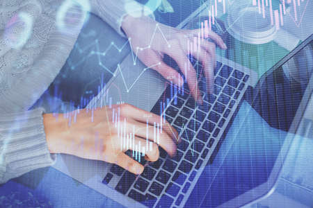 Double exposure of woman hands typing on computer and forex chart hologram drawing. Stock market...