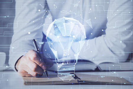 View of Bulb lamp idea concept icon on a futuristic interface with writing man's hand background....