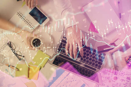 Multi exposure of man's hands typing over computer keyboard and forex graph hologram drawing. Top...