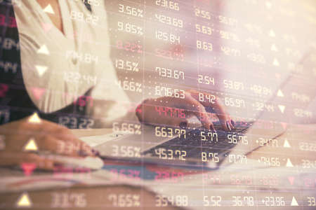 Double exposure of businesswoman hands typing on computer and forex graph hologram drawing....