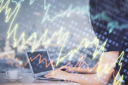 Double exposure of businesswoman hands typing on computer and forex chart hologram drawing....