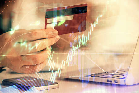 Multi exposure of woman on-line shopping holding a credit card and financial graph drawing. Stock...
