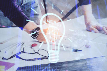 View of Bulb lamp idea concept icon on a futuristic interface with writing man's hand background. Double exposure.の写真素材